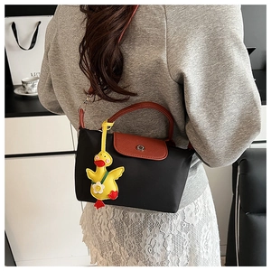 Detail of black nylon tote bag with brown leather flap and yellow duck pendant