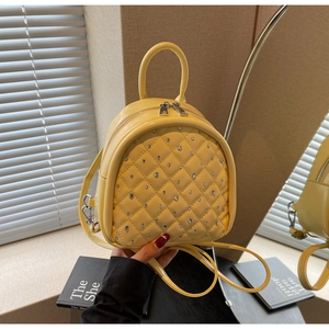 Close-up of yellow quilted PU leather mini backpack with silver rhinestone studs decoration