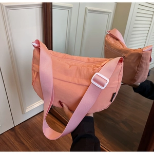 Detail of peach nylon crescent crossbody bag with wide strap and plastic buckle