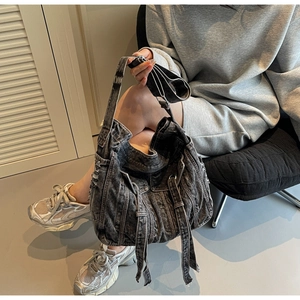 Detail of distressed dark grey denim tote bag with frayed edges and long straps