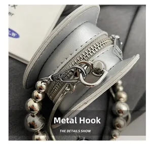 Detail of silver mini crossbody bag showing metal hook and beaded chain strap