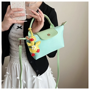Detail of mint green square handbag with gold hardware and a cute yellow duck charm