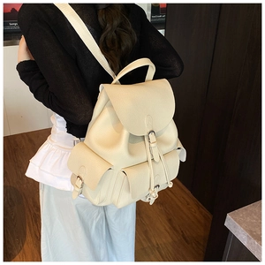 Close-up of beige pebble leather backpack featuring silver buckles and layered pockets