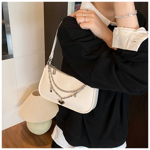 Detail of creamy white leather baguette bag with silver chain and heart pendant