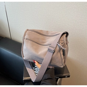 Detail of tan multi-pocket nylon crossbody bag with adjustable wide shoulder strap