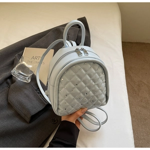 Close-up of light blue quilted mini backpack with rhinestone detailing and dual metal zippers
