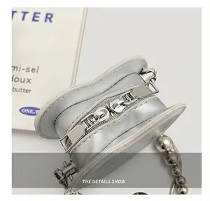Close-up of silver heart-shaped mini bag featuring dual zippers and pearl bead chain
