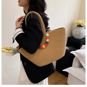 Détail d'un grand sac cabas en paille tressée avec des pompons colorés décoratifs