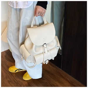 Detailed view of cream white backpack featuring lychee grain texture and silver buckles