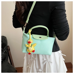 Detail of mint green small square handbag with a cute yellow duck pendant accessory