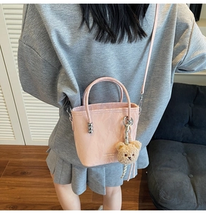 Mini borsa a secchiello rosa con ciondolo a forma di orso indossata a tracolla