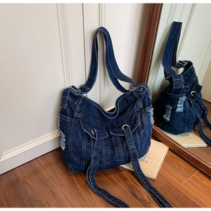 Detailed view of dark blue denim tote bag with cargo pockets and distressed edges