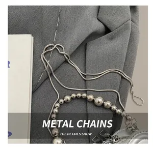 Detail of silver metallic snake chain and beaded strap on mini leather handbag