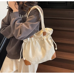 Detail of canvas drawstring tote bag with brown leather base and rope closure