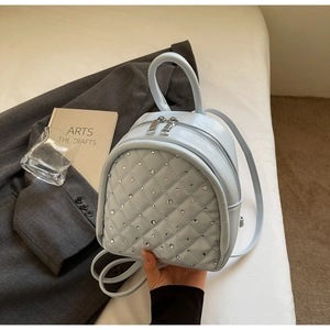 Detail of light blue quilted mini backpack featuring sparkling rhinestone embellishments