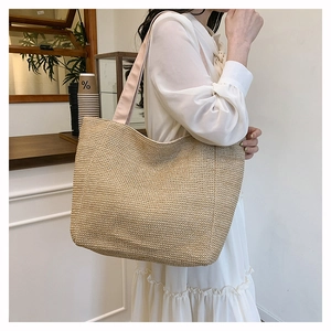 Detailed view of woven straw tote bag featuring pink wide strap and natural texture