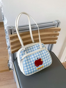 Blue checkered tote bag with red apple patch and white handles on a chair back
