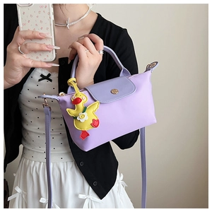 Detail of purple nylon handbag featuring a leather flap and cute yellow duck charm accessory