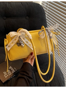 Yellow faux leather crossbody bag with lace bow, ribbon, and heart charm accessory