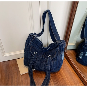 Detail of vintage blue denim tote bag featuring dual front pockets and frayed edges