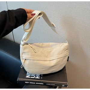 Detail of a beige nylon crescent crossbody bag with a drawstring zipper pocket