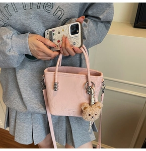 Dettaglio borsa a secchiello rosa con logo a rilievo e ciondolo orsetto carino