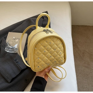Close-up of quilted diamond pattern with rhinestones on light yellow mini backpack