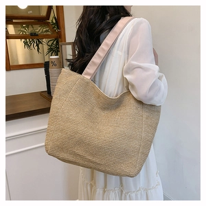 Detail showing the side view of the woven straw tote bag with wide pink canvas straps