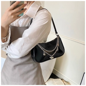 Chic black patent leather underarm bag with decorative silver chains and heart charms