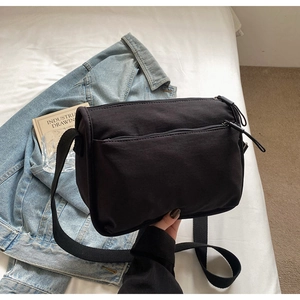 Detail of black nylon crossbody bag with multi-zipper pockets and adjustable strap