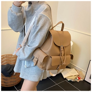Detail of warm khaki leather backpack with flap drawstring and front pocket on model