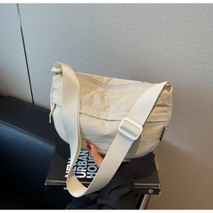 Detail of cream white nylon crescent bag showing textured fabric and zipper closure