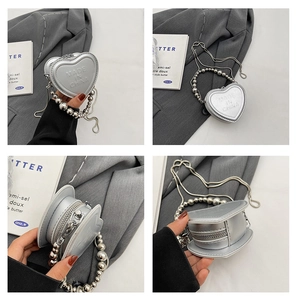 Detail view of silver heart-shaped mini bag showing embossed text and bead chain strap