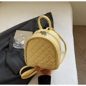 Detail of light yellow quilted mini backpack with rhinestone decor and double zippers
