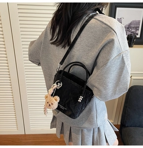 Dettaglio della mini borsa a secchiello nera increspata con ciondolo a forma di orsetto