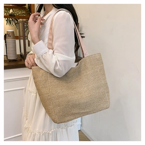 Close-up of woven straw tote bag with pink fabric straps in a bright cafe setting