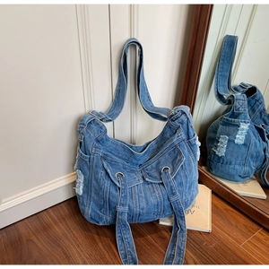 Detailed close-up of distressed denim tote bag with vintage pockets and frayed edges