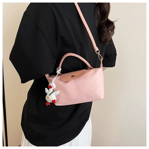 Detail view of pink nylon handbag with leather flap and cute white duck pendant accessory