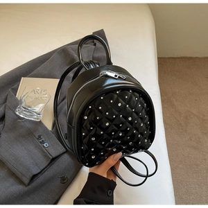 Chic black quilted mini backpack featuring rhinestone accents on a soft white surface