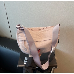 Detail of mauve nylon crescent bag with front zipper pocket and wide adjustable strap