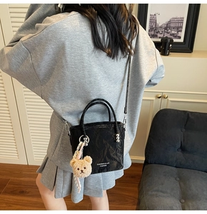 Détail d'un sac seau noir plissé avec breloque ours et bandoulière réglable