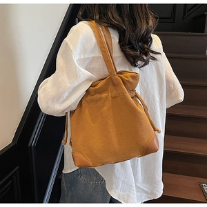 Detail of canvas bucket bag with leather reinforced corners and drawstring closure