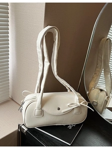 Cremefarbene Boston-Zylindertasche mit Schleife und silbernem Magnetverschluss im Studio