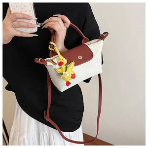 Detail of crossbody mini bag in beige and brown with cute duck charm and gold buckle