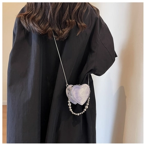 Detailed macro view of heart-shaped mini bag with purple tie-dye texture and bead chain