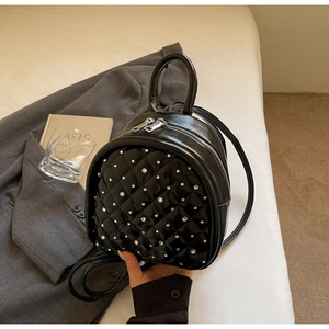 Close-up of quilted black mini backpack with silver rhinestone studs and metal zippers