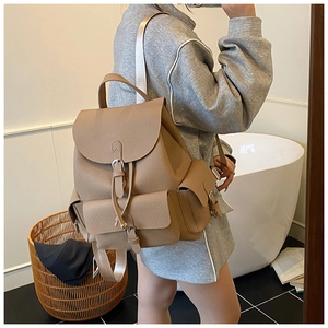 Side view of beige leather backpack showing large capacity and textured pebble finish