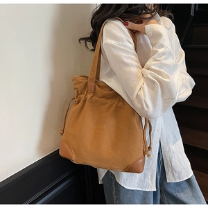 Detailed view of canvas tote bag with leather corner reinforcements and drawstring closure