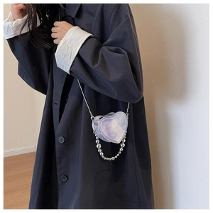 Detail of heart-shaped mini crossbody bag with marble texture and silver chain straps