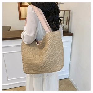 Detail of woven straw tote bag with pink straps showing texture and shoulder fit